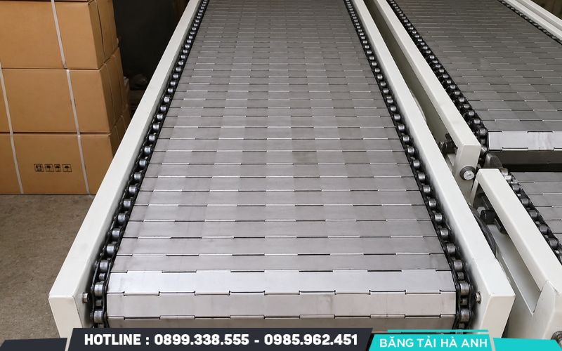 Băng tải xích inox là thiết bị vận chuyển sử dụng các mắt xích hoặc tấm xích bằng inox liên kết chặt chẽ
