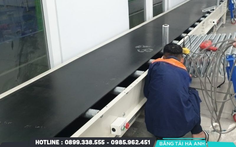 Tăng độ căng của dây băng bằng cách điều chỉnh hệ thống vít kích hoặc tạ đối trọng ở cuối băng tải